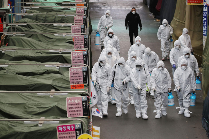 Petugas menyemprotkan disinfektan di depan sekte Gereja Sincheonji di Daegu yang menjadi lokasi penyebaran virus corona terbesar di Korsel. AFP Photo/Yonhap