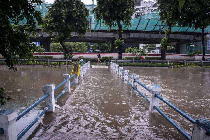 Seorang warga berjalan di dekat jembatan yang terendam luapan sungai di kawasan Jalan HR Rasuna Said, Jakarta, Selasa. ANTARA FOTO/Aprillio Akbar