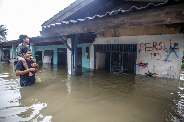 Warga melintas di depan rumah yang terendam banjir di kawasan Cilangkap, Jakarta Timur. ANTARA FOTO/Yulius Satria Wijaya