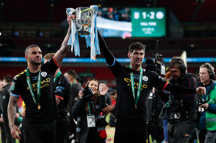 Pemain belakang City Kyle Walker (kiri) dan John Stones menangkat trofi Piala Liga Inggris 2019/20.