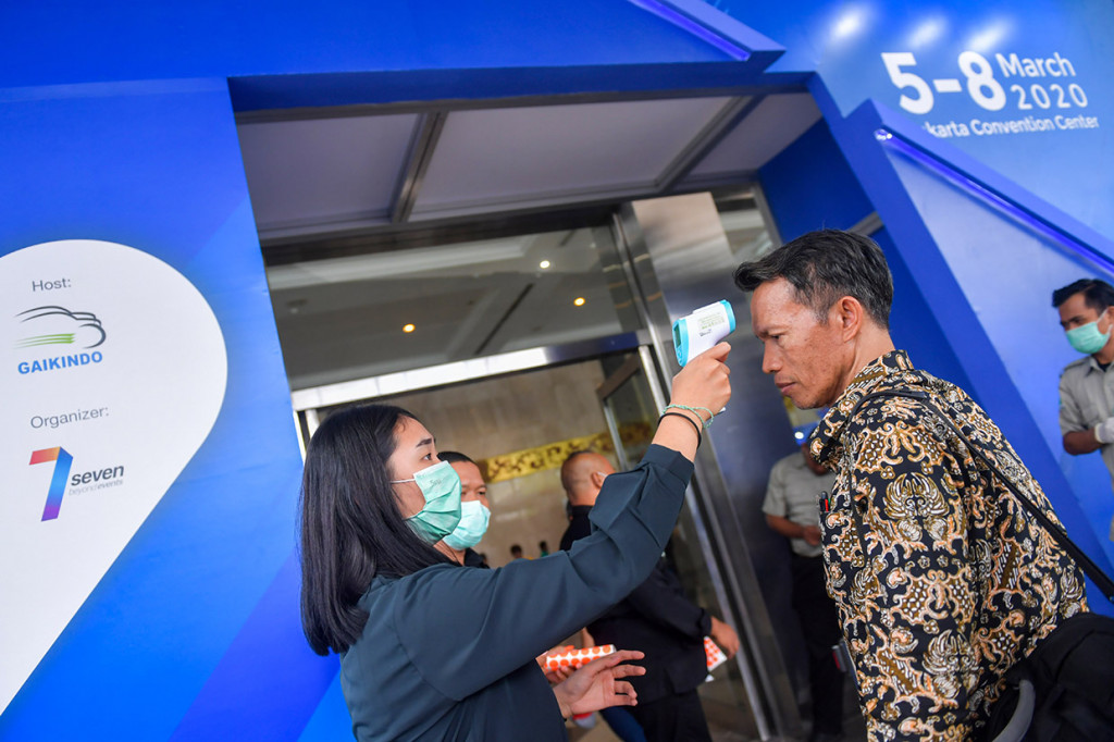 Petugas memeriksa suhu tubuh dari pengunjung pameran kendaraan komersial, Gaikindo Indonesia International Commercial Vehicle Expo (GIICOMVEC) di Jakarta Convention Center, Jakarta Pusat.