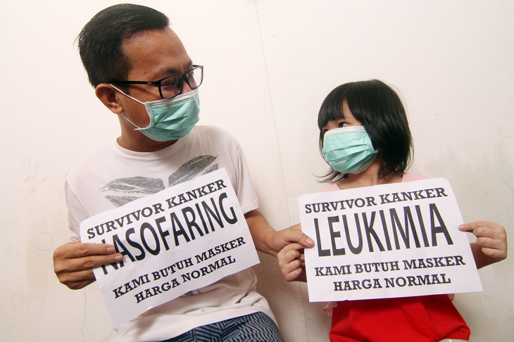 Penyintas kanker yaitu Susanto Tan (kiri) dan anaknya Celine memegang kertas bertuliskan membutuhkan masker, di kediaman mereka di Kecamatan Jungkat, Kabupaten Mempawah, Kalimantan Barat, Jumat, 6 Maret 2020. 