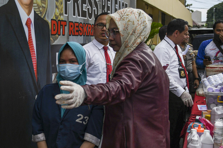 Anggota Ditkrimsus Polda Sumatera Selatan menggiring tersangka penjual kosmetik ilegal saat rilis kasus kosmetik ilegal di Polda Sumatera Selatan, Palembang.