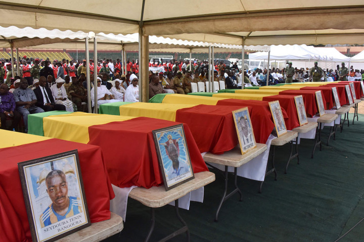 Kerabat dan pejabat duduk di sebelah peti mati para pemain Etoile de Guinee, tim sepak bola divisi dua Guinea, selama prosesi pemakaman di Conakry, Senin, 9 Maret 2020 waktu setempat.