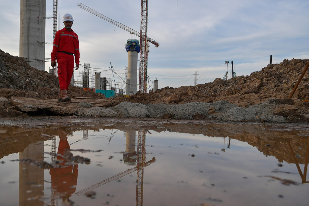 Pekerja melintas di proyek pembangunan 'Jakarta International Stadium' atau Stadion Bersih, Manusiawi dan Wibawa (BMW) di kawasan Papanggo, Tanjung Priok, Jakarta.
