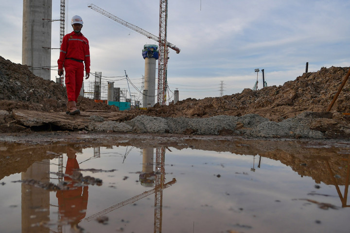 Pekerja melintas di proyek pembangunan 'Jakarta International Stadium' atau Stadion Bersih, Manusiawi dan Wibawa (BMW) di kawasan Papanggo, Tanjung Priok, Jakarta.
