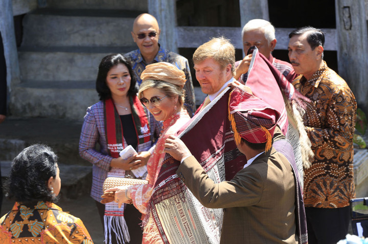 Raja Belanda Willem Alexander bersama Ratu Maxima Zorreguieta Cerruti (tengah) didampingi Menteri Koordinator Bidang Kemaritiman dan Investasi Luhut Binsar Pandjaitan (kanan) dihadiahi kain ulos Pinunsaan ketika disambut oleh masyarakat Batak di Dusun Siambat Dalan, Desa Lintong Nihuta, Kecamatan Tampahan, Kabupaten Toba, Sumatera Utara.
