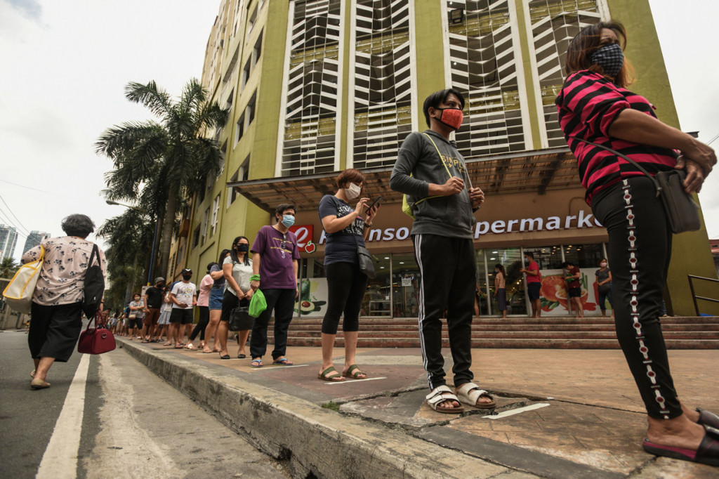 Tampak warga sedang mengantre dengan tertib dengan berdiri di dekat garis yang telah ditentukan. AFP Photo/Maria Tan