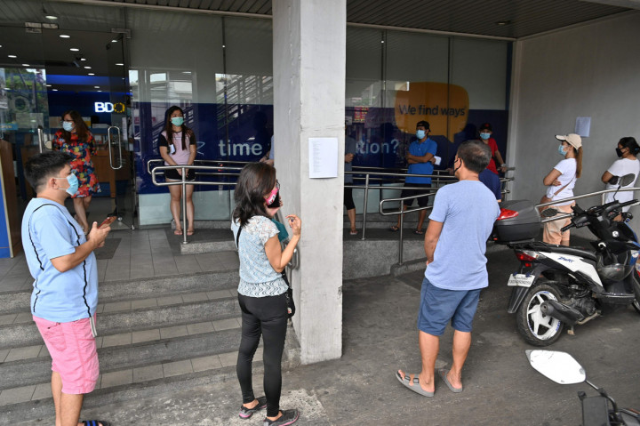 Warga mengantre dengan jarak satu meter di sebuah bank di Manila. AFP Photo/Ted Aljibe