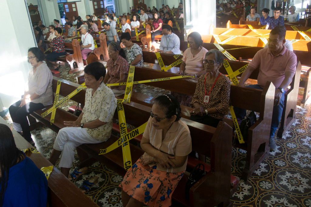 Masih di Filipina, Bangku-bangku di gereja dipasangi garis polisi untuk memberi jarak satu orang dengan orang lainnya. AFP Photo/Alren Beronio