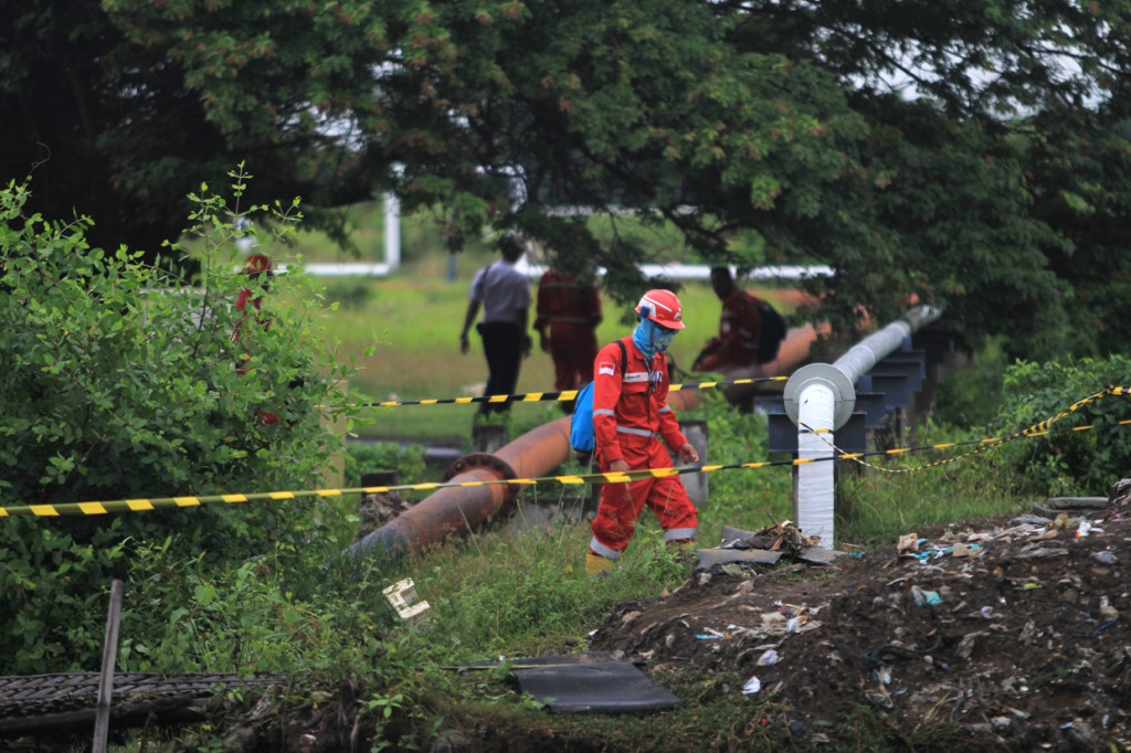 Pekerja melakukan pembersihan di saluran pipa Pertamina yang mengalami kebocoran di desa Majalerta, Balongan, Indramayu, Jawa Barat. 

