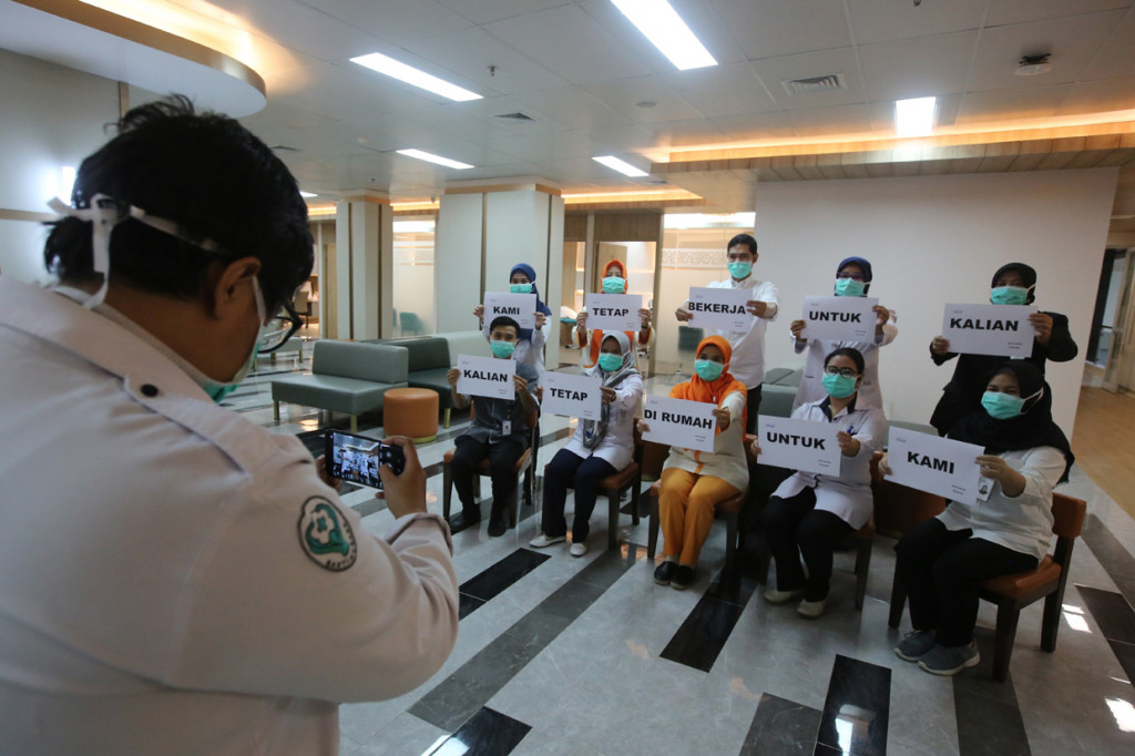 Petugas medis melakukan foto dengan memegang tulisan