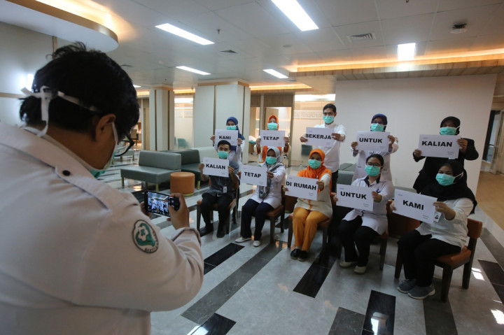 Petugas medis melakukan foto dengan memegang tulisan
