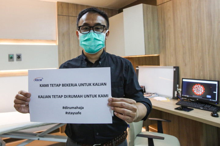 Petugas medis melakukan foto dengan memegang tulisan