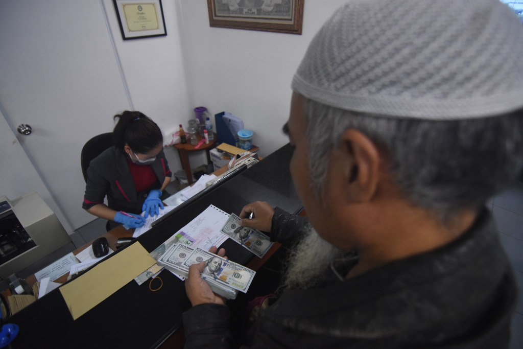 Pengunjung menukarkan mata uang dolar AS di salah satu gerai penukaran uang asing di Jakarta.
