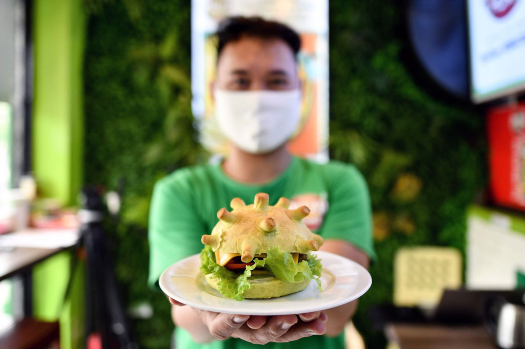 Pemilik toko roti Pizza Home, Hoang Tung memperlihatkan burger ciptaannya yang bertema coronavirus di Hanoi, Kamis, 26 Maret 2020.