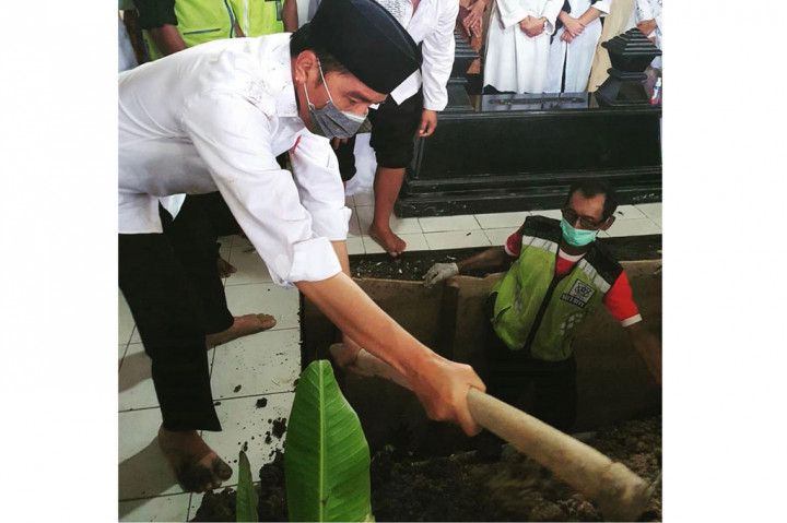 Foto lainnya menunjukkan Presiden memasukkan tanah ke liang lahat menggunakan cangkul. Tanah mengotori kemejanya.