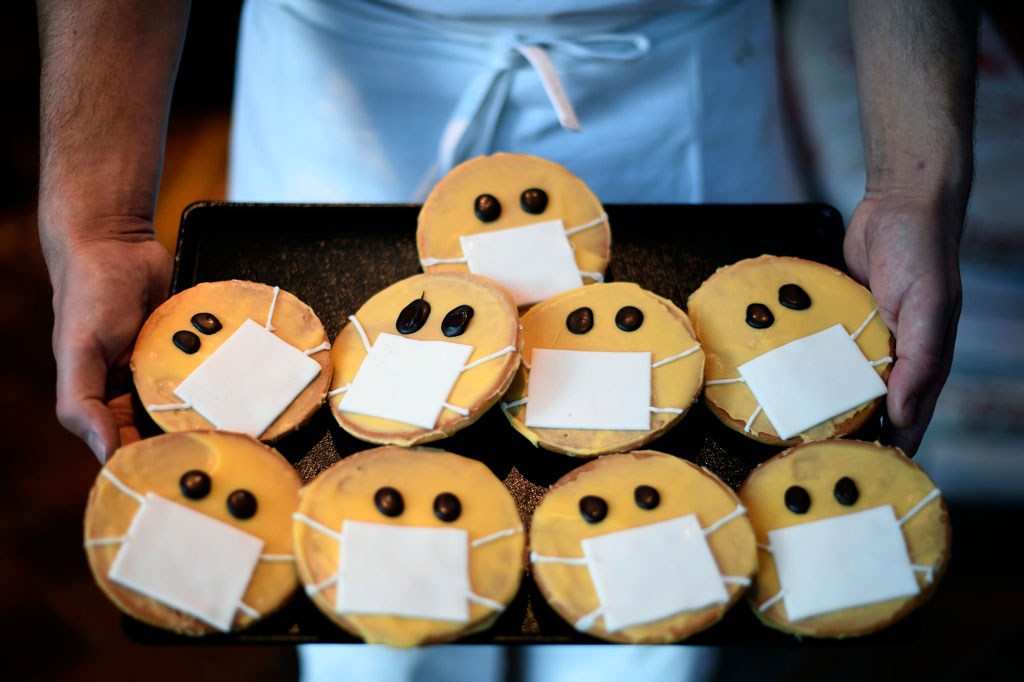 Seorang tukang roti menunjukkan biskuit yang berbentuk wajah dengan masker di toko roti Schuerener Backparadies di Dortmund, Jerman, pada Kamis, 26 Maret 2020 waktu setempat. 