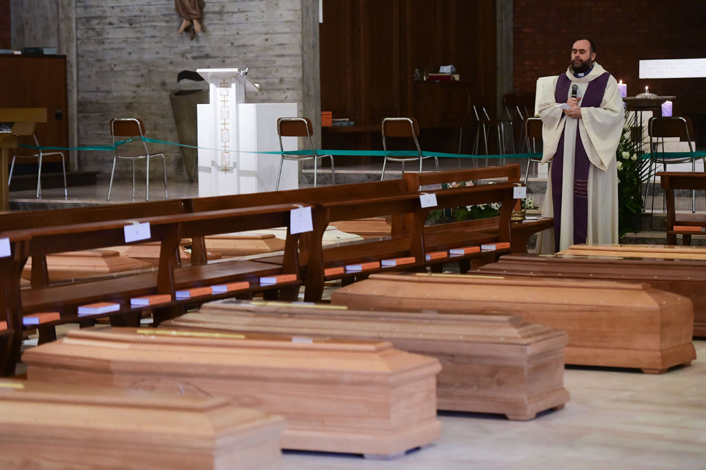 Pastor Don Marcello memberikan berkat kepada peti mati yang berizi jenazah korban virus korona (covid-19), di Gereja San Giuseppe di Seriate, Italia, Jumat, 28 Maret 2020.