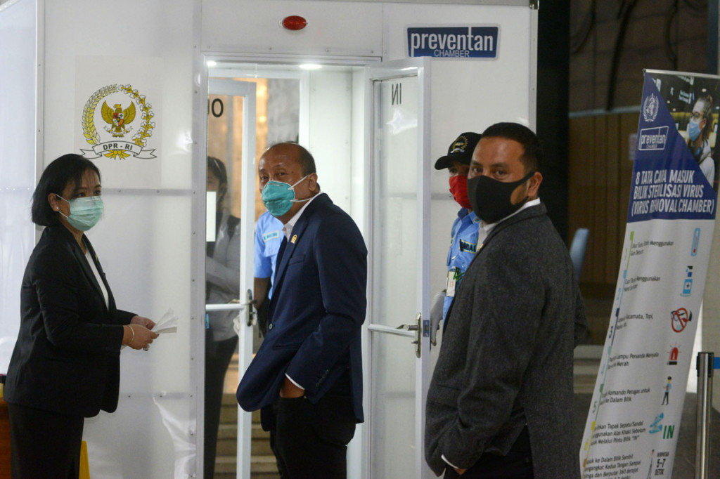 Angota DPR Fraksi NasDem yang juga Sekretaris Fraksi NasDem DPR, Saan Mustopa antri masuk dalam Box Disinfektan sebelum Rapat Paripurna untuk membuka masa sidang di tengah wabah virus covid-19.