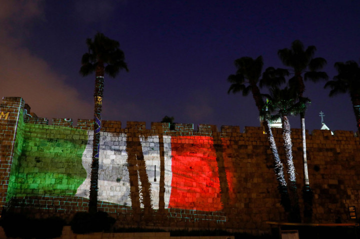 Bendera Italia diproyeksikan di dinding benteng Kota Tua Yerusalem untuk menunjukkan dukungan bagi mereka yang terjangkit virus korona di Italia. AFP PHOTO/Menahem Kahana