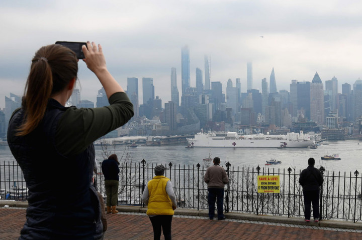 Warga menyambut kedatangan kapal rumah sakit militer USNS Comford di New York, Senin, 30 Maret 2020 waktu setempat.
