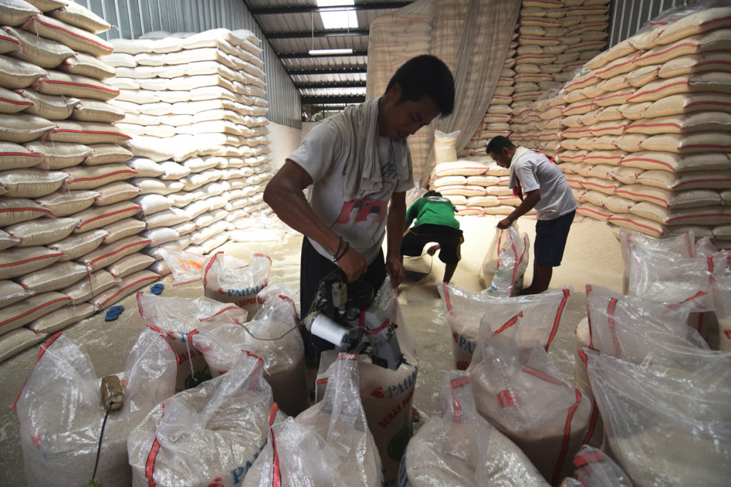 Pekerja mengemas beras di Pasar Induk Beras Cipinang, Jakarta.