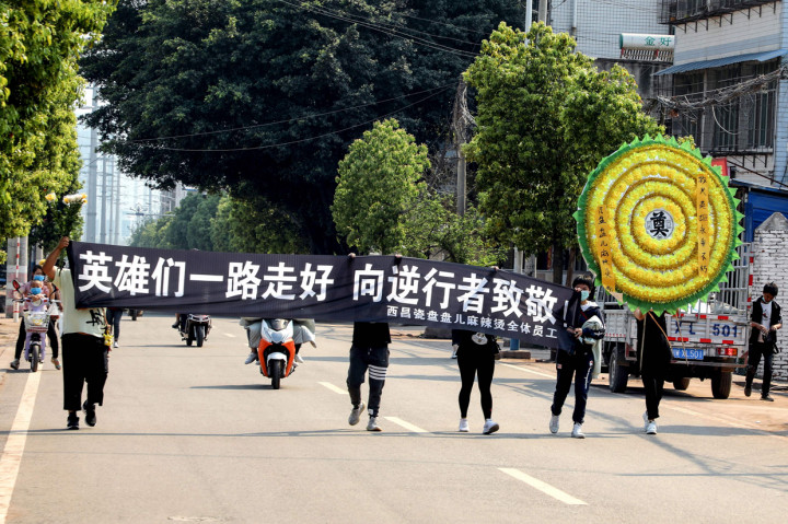 Sejumlah orang membawa banner menunjukkan penghormatan kepada pemadam kebakaran dan seorang pemandu yang tewas ketika berjuang memadamkan kebakaran hutan. 
