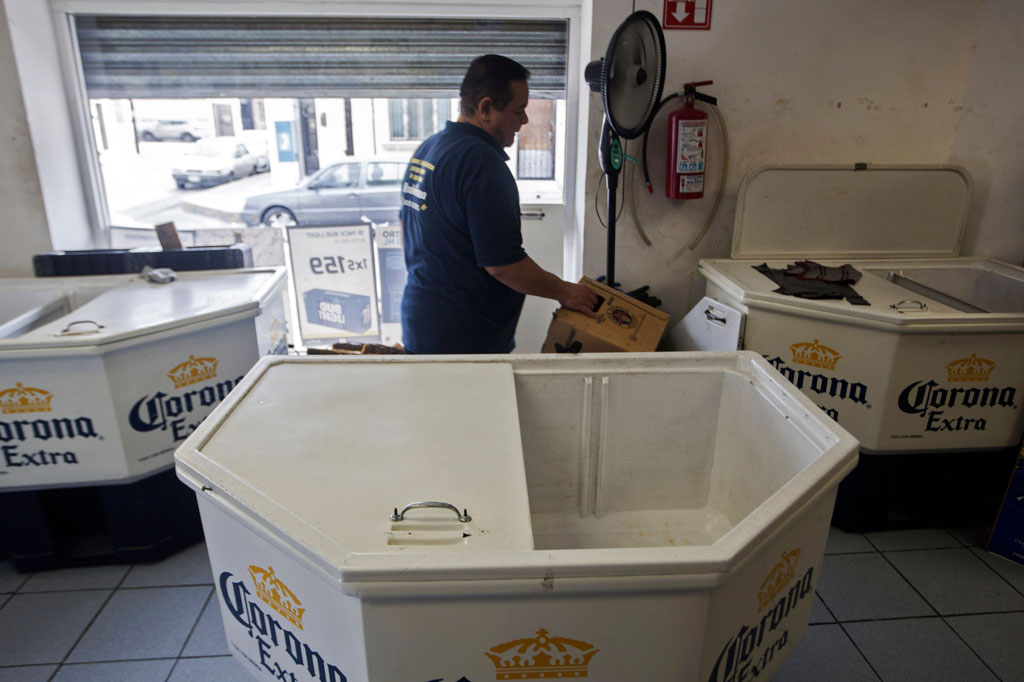 Seorang pekerja berada di dalam toko di antara kulkas bir Corona yang telah kosong di Monterrey,  Nuevo Leon, Meksiko, Jumat, 3 April 2020 waktu setempat.