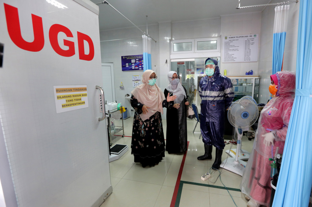 Ketua Komisi IV DPRK Banda Aceh Tati Meutia Asmara (kiri) berbincang dengan petugas medis Puskesmas Meuraxa yang memakai jas hujan plastik sebagai Alat Pelindung Diri (APD) untuk melayani pasien di Banda Aceh, Aceh. 