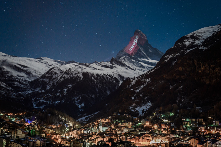 Seniman cahaya Swiss Gerry Hofstetter mengirim pesan solidaritas kepada mereka yang terinfeksi virus korona (covid-19) di resor pegunungan Zermatt, Swiss. AFP Photo/Fabrice Coffrini