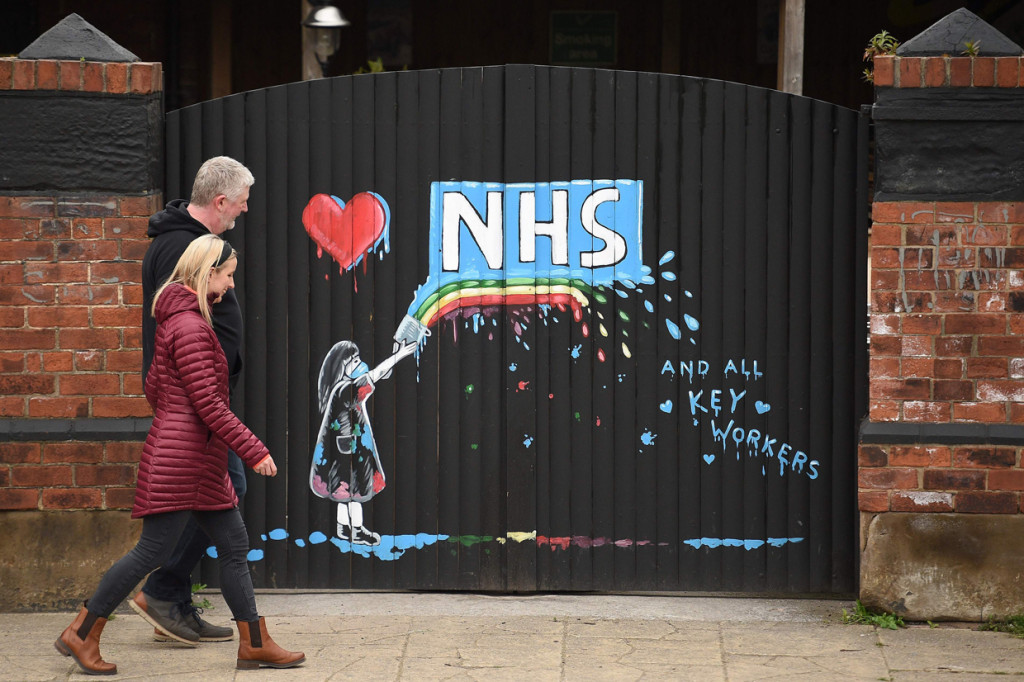 Graffiti yang menggambarkan logo Layanan Kesehatan Nasional Inggris (NHS) dan pelangi, sebagai tanda cinta dan terima kasih kepada staf NHS dan semua pihak yang terlibat dalam merawat pasien Covid-19, digambarkan di gerbang ke sebuah pub tertutup di Pontefract, Inggris. AFP Photo/Oli Scarff
