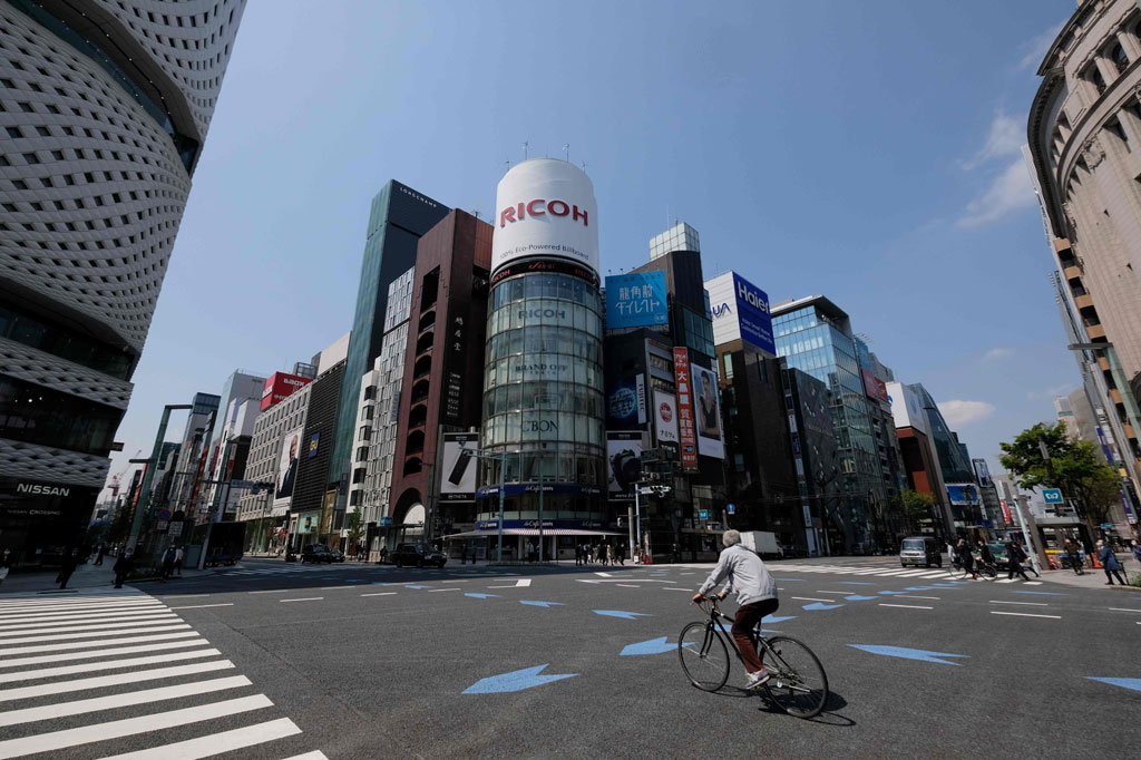 Seorang pria yang mengendarai sepeda melewati persimpangan jalan yang relatif sepi di distrik Shoppig Tokyo, Ginza, pada 8 April 2020, hari pertama pemberlakukan keadaan darurat akibat wabah covid-19.