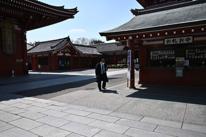 Seorang pria yang memakai masker berjalan di halaman Kuil Sensoji di Tokyo pada 8 April 2020. 