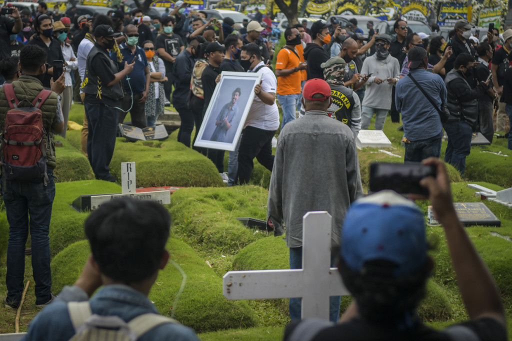 Kerabat membawa foto penyanyi Glenn Fredly saat pemakaman di TPU Tanah Kusir, Jakarta.