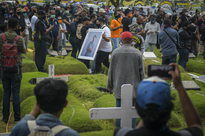 Kerabat membawa foto penyanyi Glenn Fredly saat pemakaman di TPU Tanah Kusir, Jakarta.