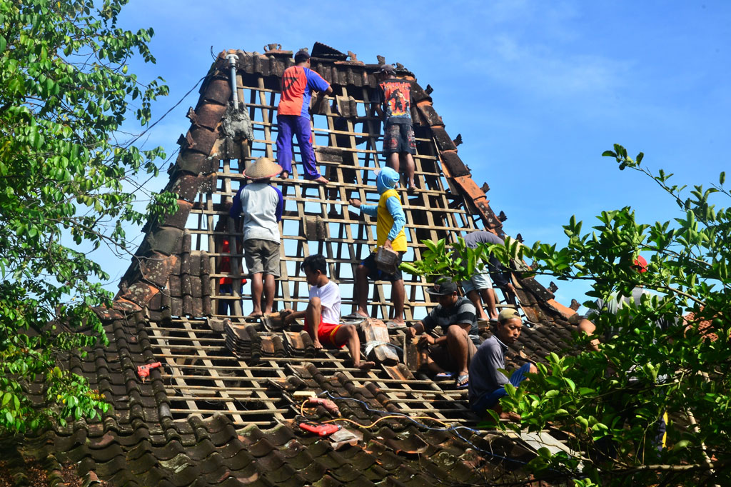 Warga memperbaiki rumah yang rusak akibat diterjang angin puting beliung di Desa Brakas, Dempet, Demak, Jawa Tengah, Sabtu, 11 April 2020.