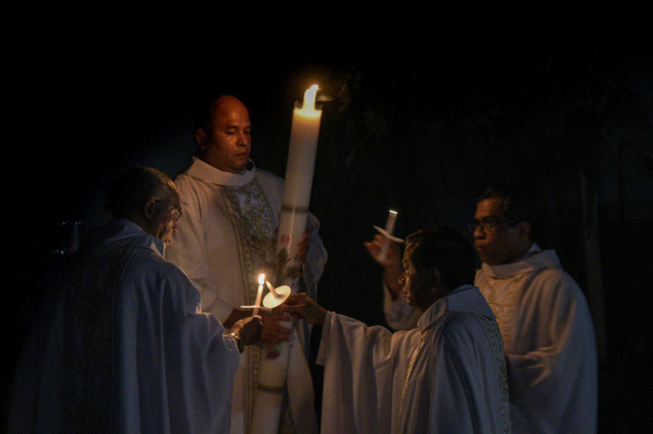 Romo Stefanus I Kadek Adi Subrata menyalakan lilin diikuti sejumlah pastur pada ibadah malam Paskah atau Sabtu Suci di Gereja Santo Arnoldus Janssen, Kota Bekasi, Jawa Barat. ANTARA Foto/Paramayuda