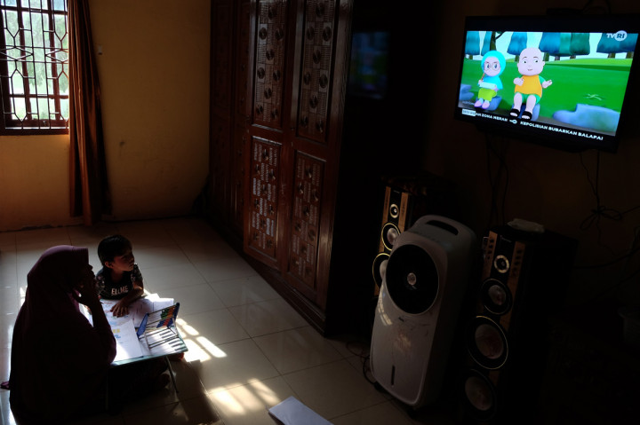Seorang anak didampingi ibunya belajar dengan melihat tayangan siaran TVRI di rumah mereka, di Deli Serdang, Sumatera Utara.