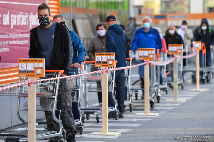 Warga yang mengenakan masker antre di luar sebuah toko di Innsbruck, Austria, Selasa, 14 April 2020, setelah negara tersebut memperlonggar kebijakan karantina nasional atau 'lockdown'.