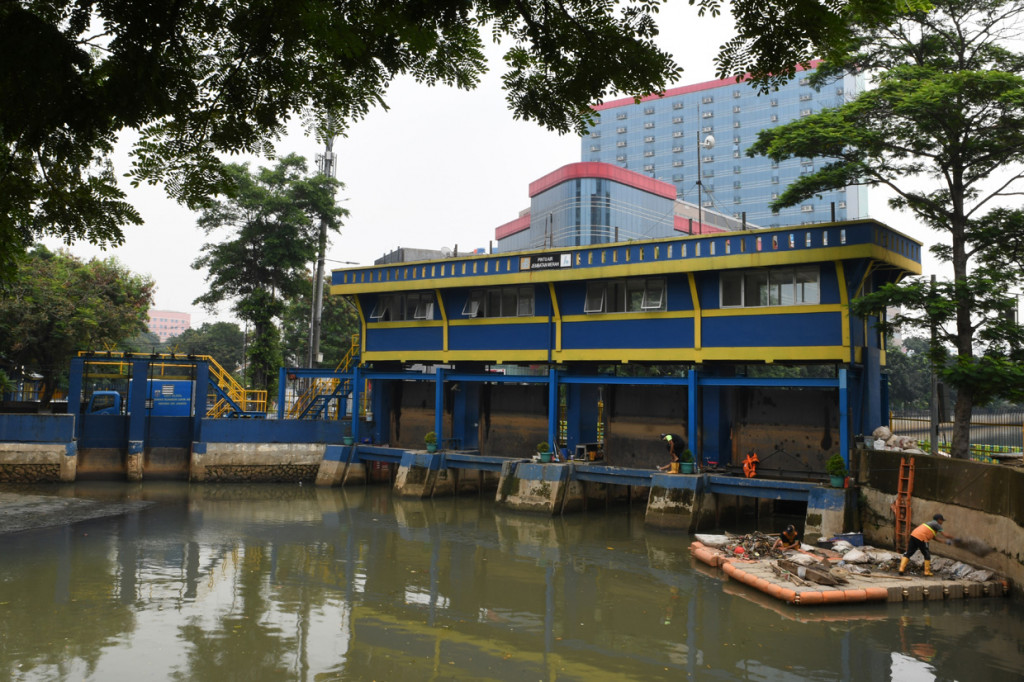 Petugas Penanganan Prasarana dan Sarana Umum (PPSU) membersihkan sampah yang berada di Pintu Air jembatan Merah, Jakarta.
