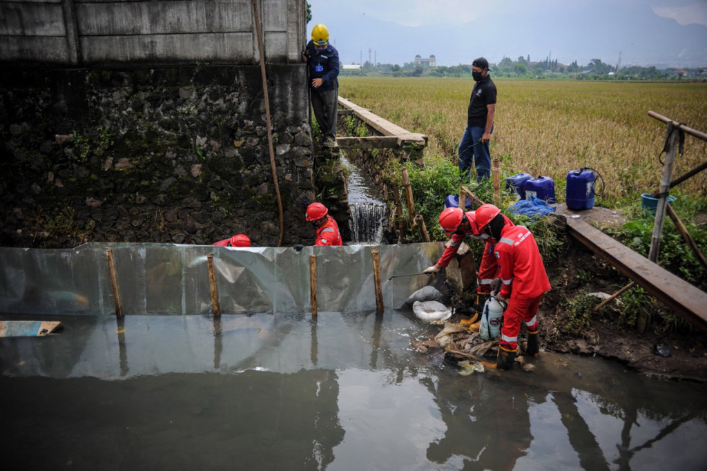 Petugas Pertamina membuat tanggul saat penanggulangan kebocoran minyak di Gedebage, Bandung, Jawa Barat.