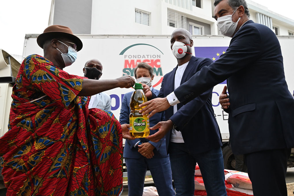 Mantan striker timnas Pantai Gading Didier Drogba (kedua kanan) disaksikan vokalis Magic System, Salif Traore, dikenal sebagai A'Salfo (kedua kiri) secara simbolis menyerahkan bantuan yang diterima seorang kepala suku di Abidjan, Jumat, 17 April 2020.
