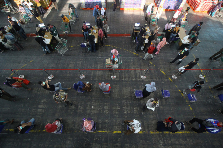 Warga antre dengan menjaga jarak untuk membeli sembako murah saat peluncuran Lumbung Pangan Jawa Timur di JX International, Surabaya, Jawa Timur.