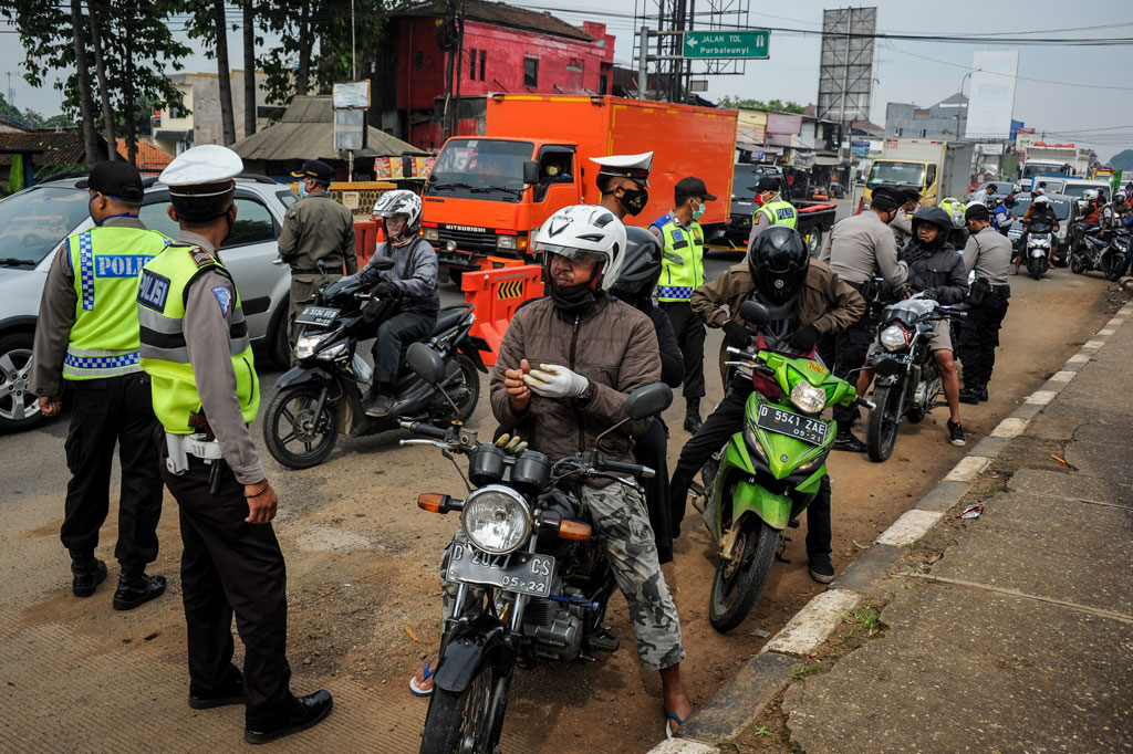 Petugas memberhentikan kendaraan bermotor di titik penyekatan larangan mudik di Jatinangor, perbatasan Kabupaten Bandung dan Kabupaten Sumedang, Jawa Barat, Sabtu, 25 April 2020. 