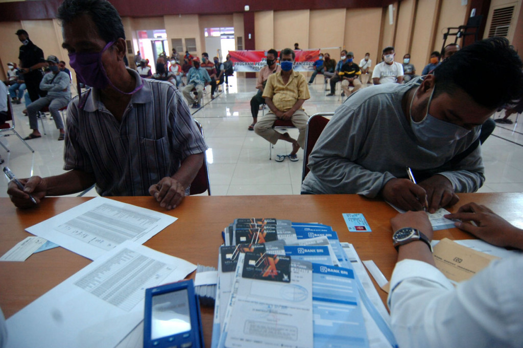 Dua supir angkutan kota (angkot) mengisi formulir pembuatan rekening tabungan saat pembagian bantuan dan pelatihan keselamatan 2020 di Tegal, Jawa Tengah.