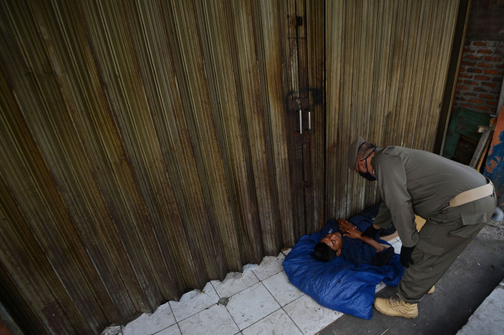 Petugas Satpol PP membangunkan seorang penyandang masalah kesejahteraan sosial (PMKS) yang tidur di emperan toko di Jalan Dewi Sartika, Cawang, Jakarta Timur.