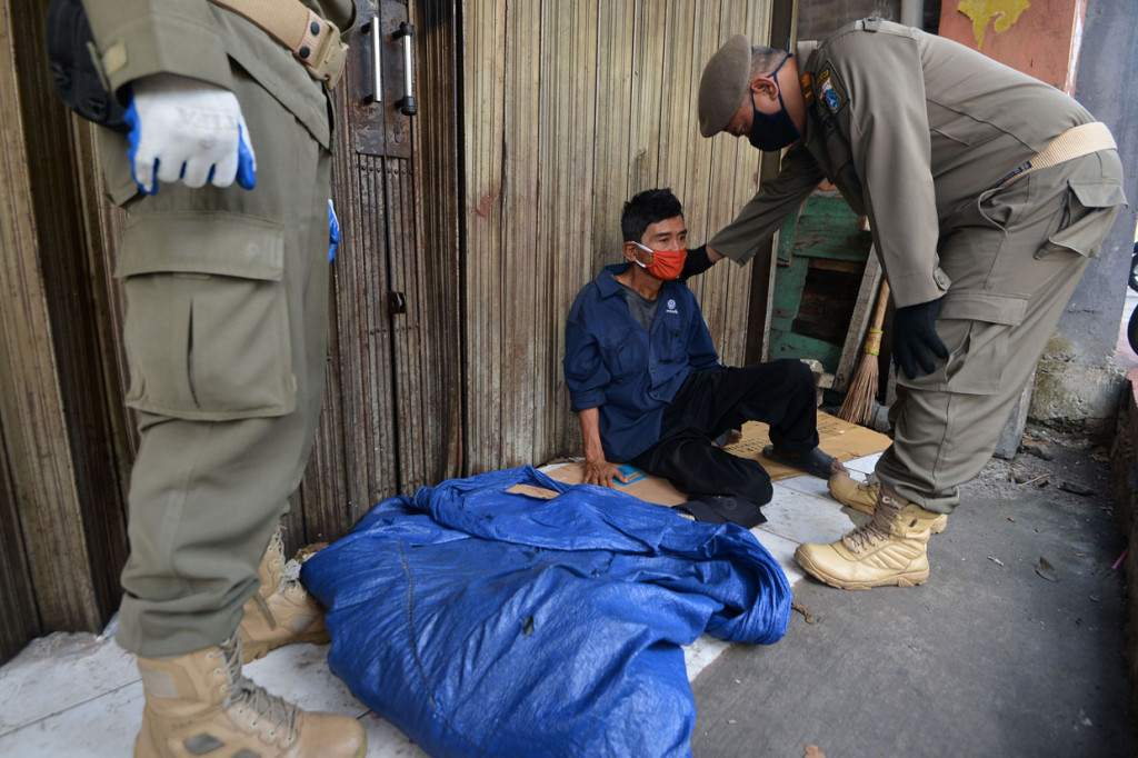 Petugas Satpol PP mengamankan seorang penyandang masalah kesejahteraan sosial (PMKS) yang tidur di emperan toko di Jalan Dewi Sartika, Cawang, Jakarta Timur.