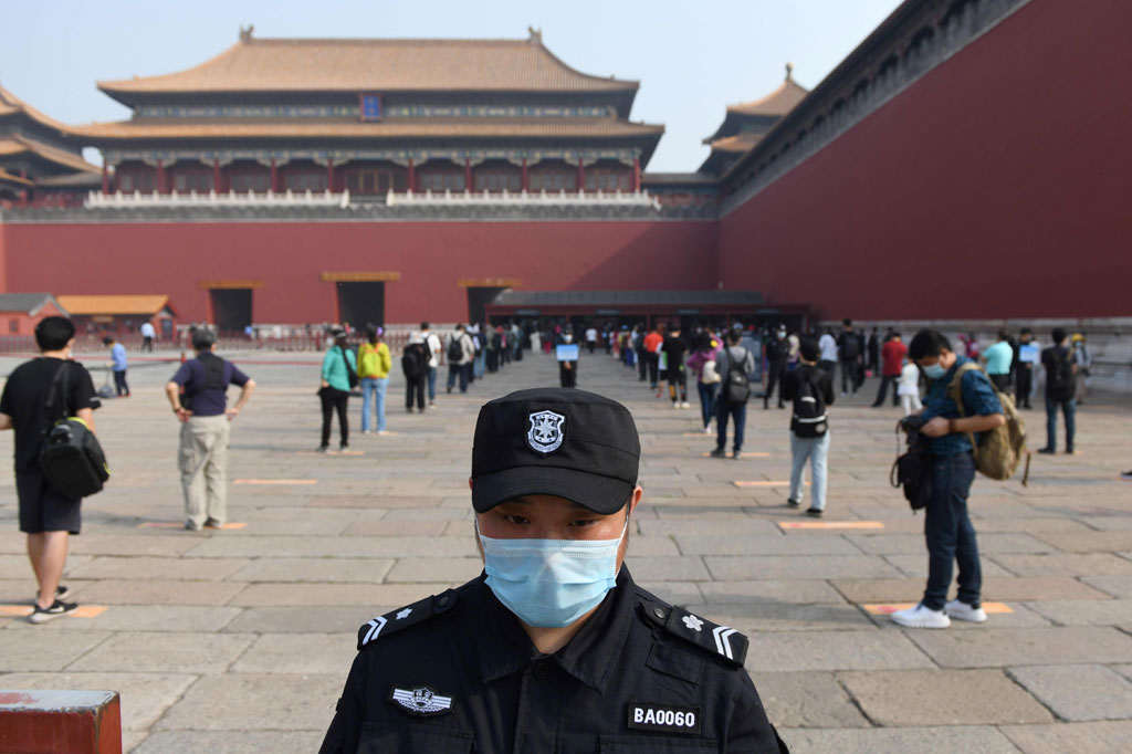 Seorang petugas keamanan berjaga-jaga saat para calon pengunjung berbaris mengantre dengan menjaga jarak sebelum memasuki bekas istana kaisar Tiongkok, Forbidden City (Kota Terlarang), di Beijing pada Jumat, 1 Mei 2020.