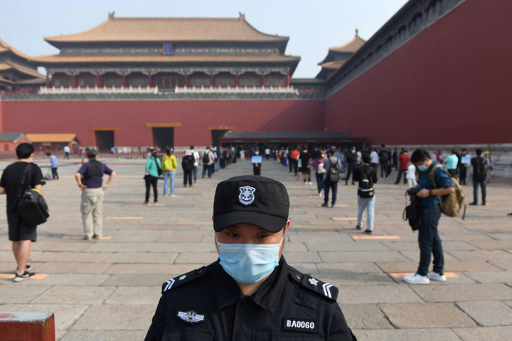 Seorang petugas keamanan berjaga-jaga saat para calon pengunjung berbaris mengantre dengan menjaga jarak sebelum memasuki bekas istana kaisar Tiongkok, Forbidden City (Kota Terlarang), di Beijing pada Jumat, 1 Mei 2020.